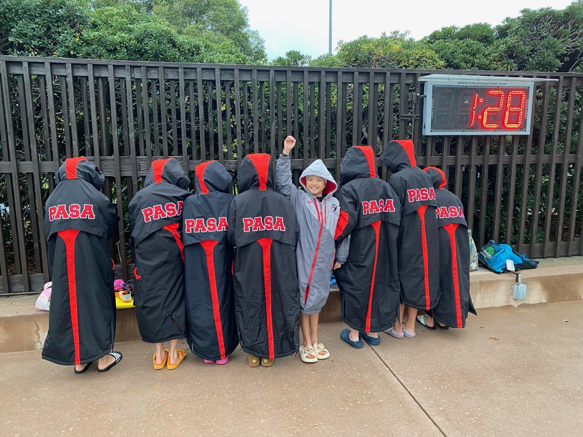 Young PASA swimmers in team parkas watching the scoreboard at Rinconada