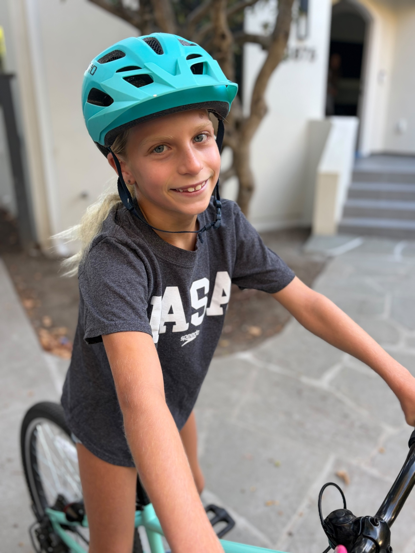 PASA swimmer in team shirt and bike helmet riding to practice